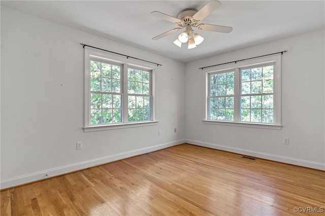 unfurnished room with a healthy amount of sunlight, baseboards, and light wood-style flooring