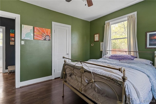 bedroom with a ceiling fan, wood finished floors, baseboards, and multiple windows