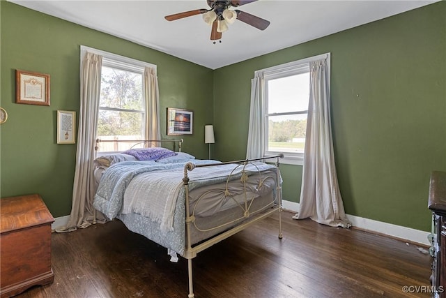 bedroom featuring baseboards, multiple windows, and wood finished floors