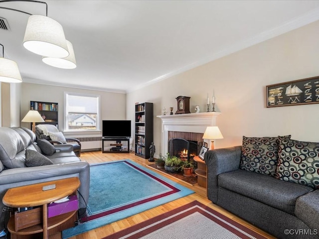 1612 Brookland Pkwy, Richmond, VA 23227 - living room featuring crown molding, wood finished floors, a brick fireplace, and radiator heating unit