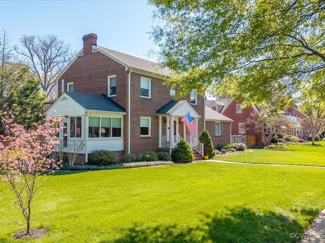 1612 Brookland Pkwy, Richmond, VA 23227 - view of front of property featuring brick siding, a front lawn, a chimney, and a sunroom