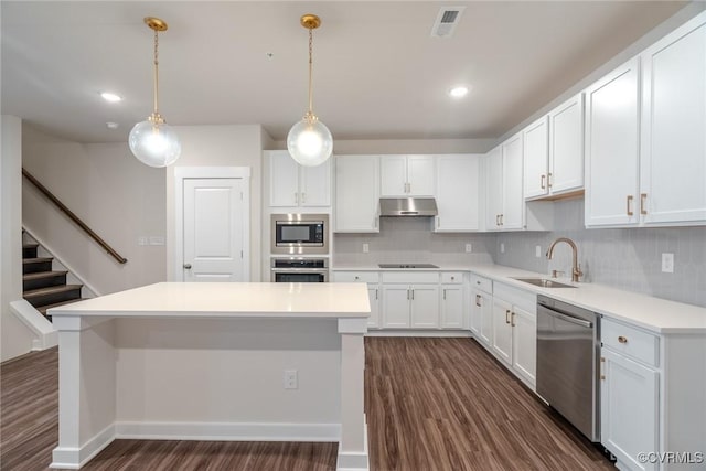 kitchen with a sink, tasteful backsplash, stainless steel appliances, and dark wood finished floors