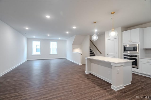 kitchen featuring a center island, stainless steel appliances, baseboards, white cabinetry, and dark wood-style floors