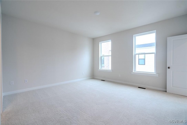 carpeted spare room featuring visible vents and baseboards