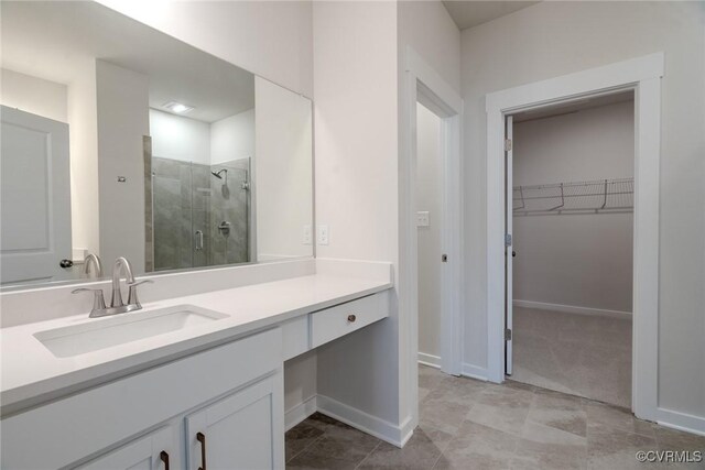 bathroom featuring vanity, baseboards, a walk in closet, and a stall shower
