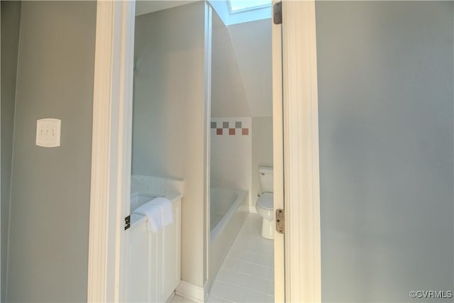 bathroom featuring toilet, a skylight, tile patterned flooring, and a bath