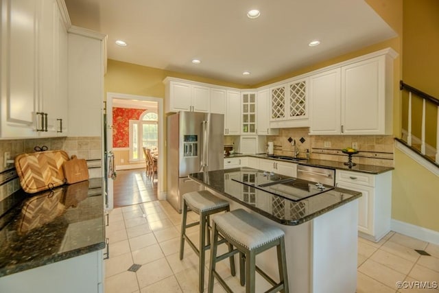 kitchen featuring a sink, appliances with stainless steel finishes, light tile patterned flooring, and a kitchen bar