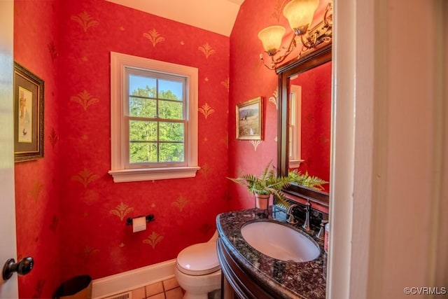 half bathroom featuring vanity, tile patterned flooring, baseboards, and toilet