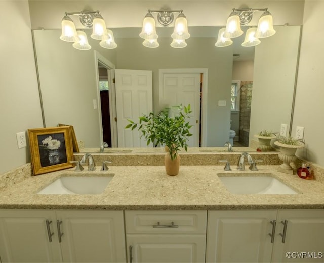 full bath with a sink, a notable chandelier, and toilet