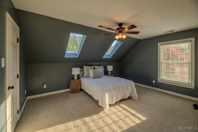 carpeted bedroom with vaulted ceiling with skylight, baseboards, multiple windows, and visible vents