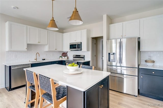 kitchen featuring light wood-type flooring, a sink, a kitchen bar, and stainless steel appliances