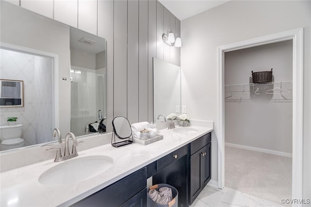 full bath with double vanity, a sink, a spacious closet, and toilet