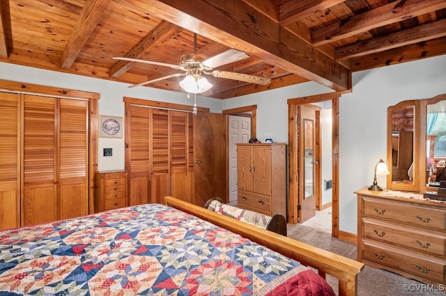 carpeted bedroom with two closets, beam ceiling, a ceiling fan, and wood ceiling