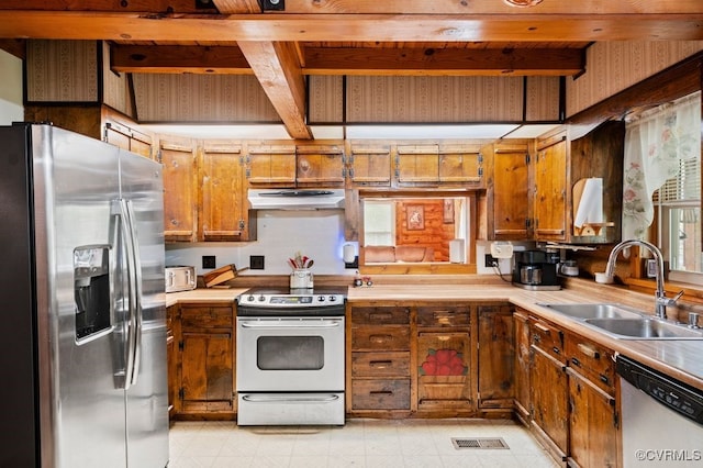 kitchen with brown cabinets, appliances with stainless steel finishes, a sink, and light countertops