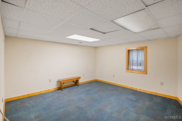 carpeted empty room with a drop ceiling and baseboards