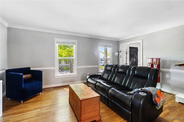 living area featuring crown molding, light wood-style floors, baseboards, and visible vents