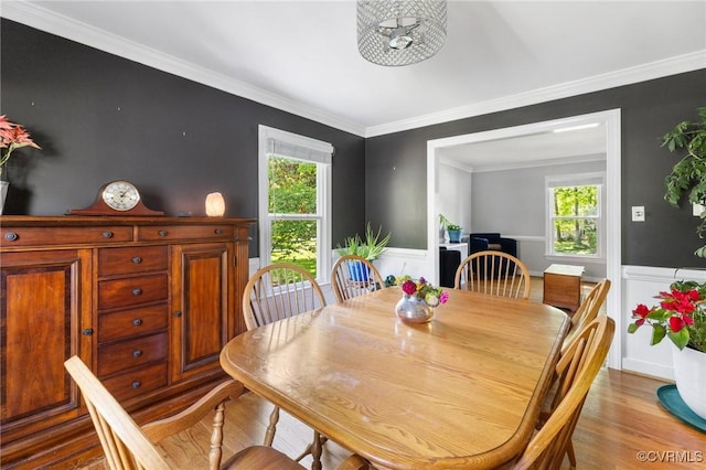dining area with ornamental molding, wainscoting, wood finished floors, and a wealth of natural light