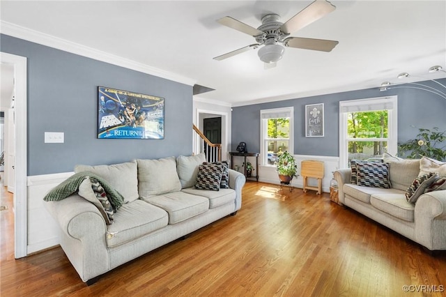 living area with a wainscoted wall, ornamental molding, and wood finished floors