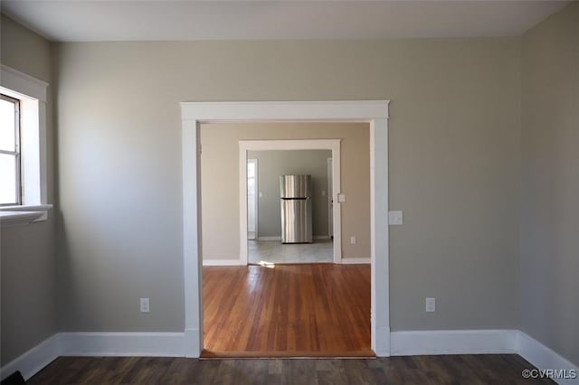 empty room with baseboards and dark wood finished floors