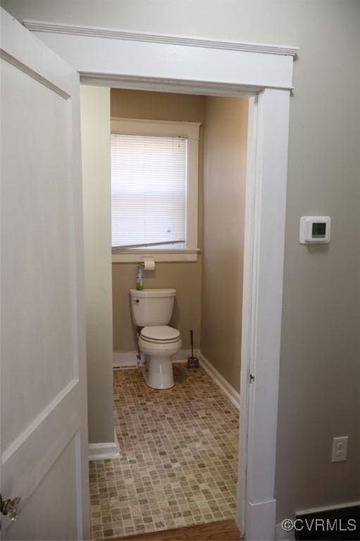 bathroom with toilet, baseboards, and tile patterned flooring