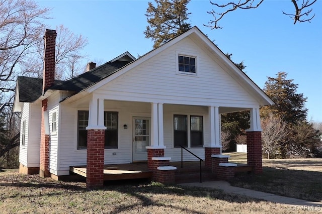 view of front of house with a chimney and covered porch
