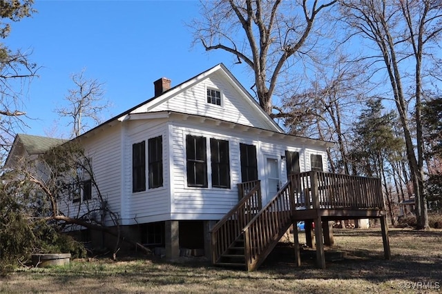 rear view of house featuring stairway, a deck, and a chimney