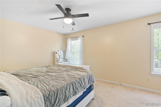 bedroom featuring baseboards, a ceiling fan, multiple windows, and light colored carpet