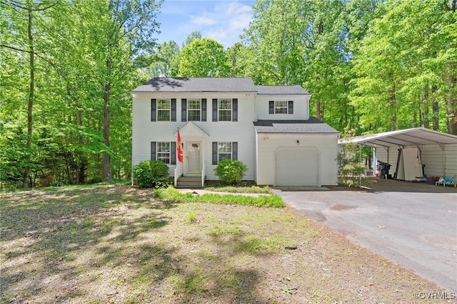 colonial inspired home featuring an attached garage, a detached carport, and aphalt driveway