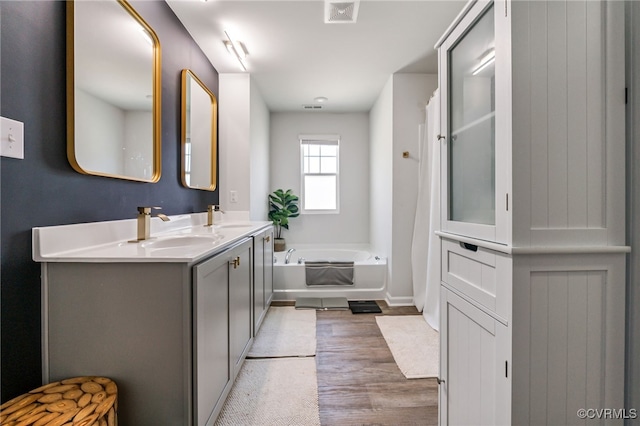 full bathroom featuring a garden tub, visible vents, a sink, and double vanity