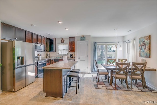 kitchen with dark brown cabinetry, stainless steel appliances, a kitchen island, and plenty of natural light