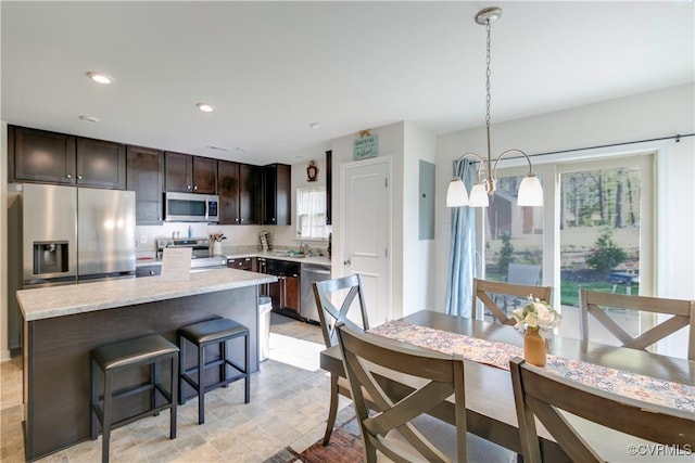 kitchen with a sink, a breakfast bar, stainless steel appliances, a center island, and dark brown cabinetry