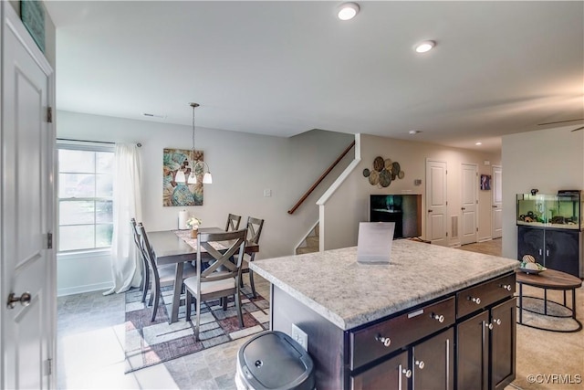 kitchen featuring recessed lighting, dark brown cabinetry, decorative light fixtures, a kitchen island, and light countertops