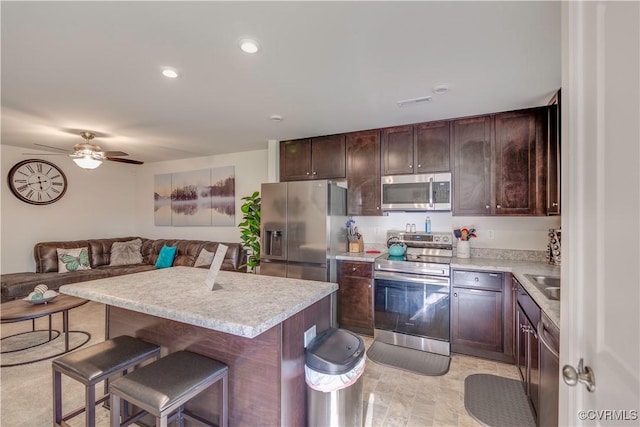 kitchen featuring appliances with stainless steel finishes, light countertops, a kitchen breakfast bar, and dark brown cabinetry