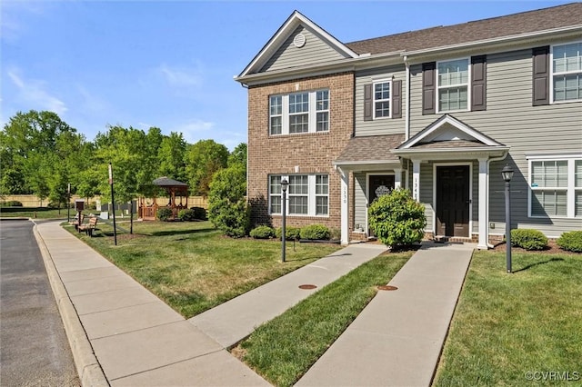 view of property with a gazebo, a front lawn, and brick siding
