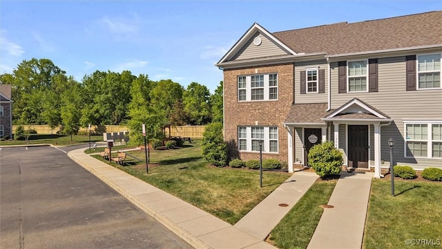 townhome / multi-family property with brick siding and a front yard