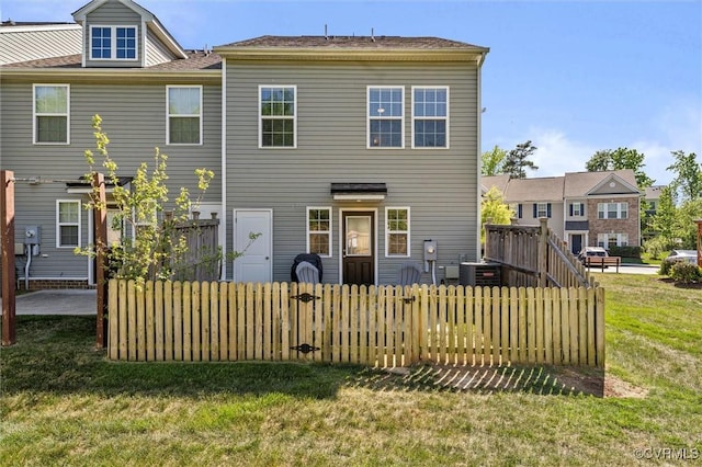 back of property with a lawn and fence