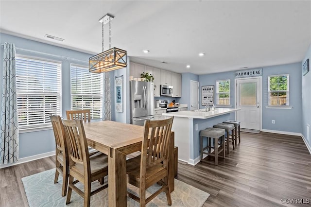 dining space with baseboards, an inviting chandelier, visible vents, and dark wood-type flooring
