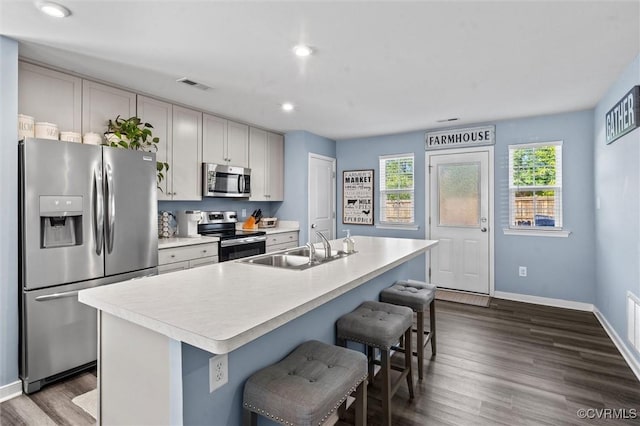 kitchen with a sink, a breakfast bar area, light countertops, stainless steel appliances, and visible vents