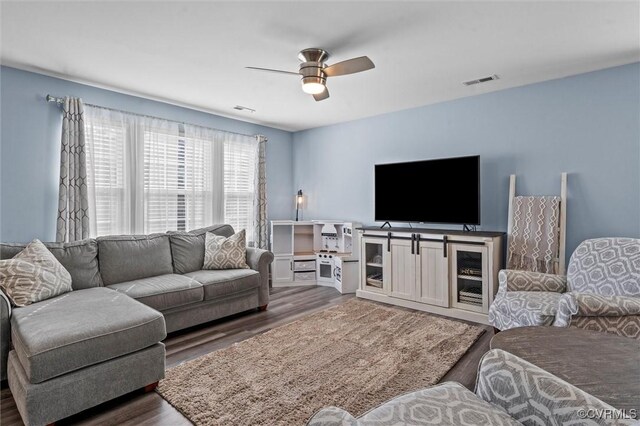 living area with ceiling fan, visible vents, and wood finished floors