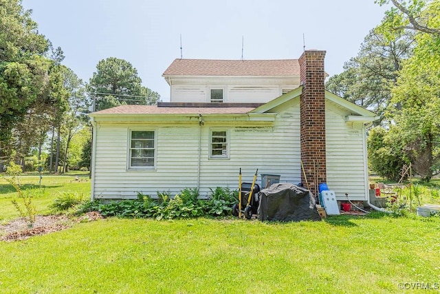 back of house featuring a lawn and a chimney