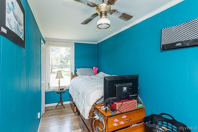 bedroom featuring crown molding, baseboards, a ceiling fan, and wood finished floors