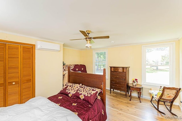 bedroom featuring a wall mounted AC, a closet, light wood-type flooring, crown molding, and a ceiling fan