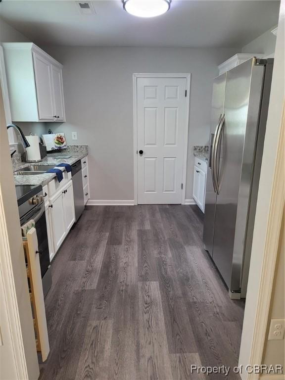 kitchen with visible vents, white cabinets, appliances with stainless steel finishes, dark wood-style floors, and light stone counters