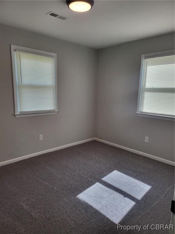 carpeted spare room featuring visible vents and baseboards