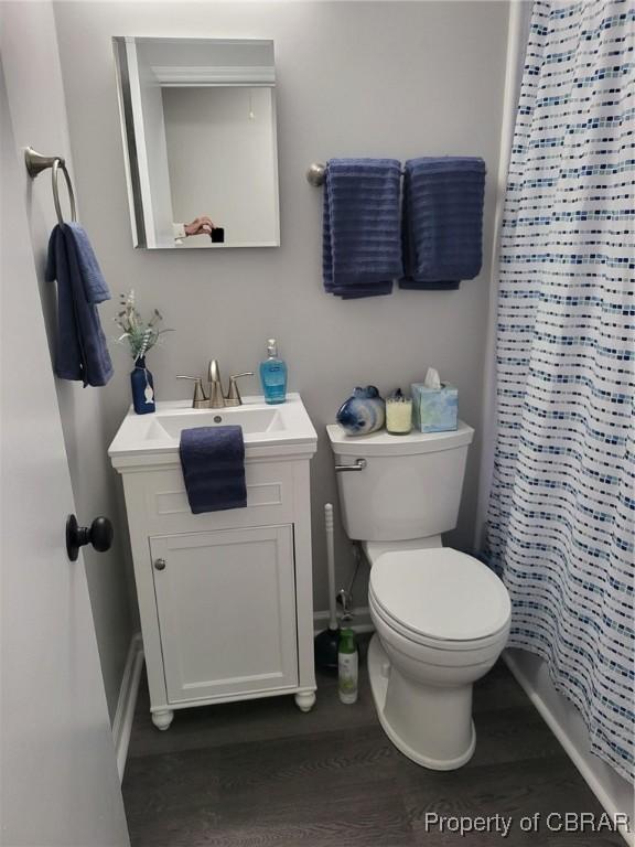 full bath featuring a shower with shower curtain, vanity, baseboards, toilet, and wood finished floors