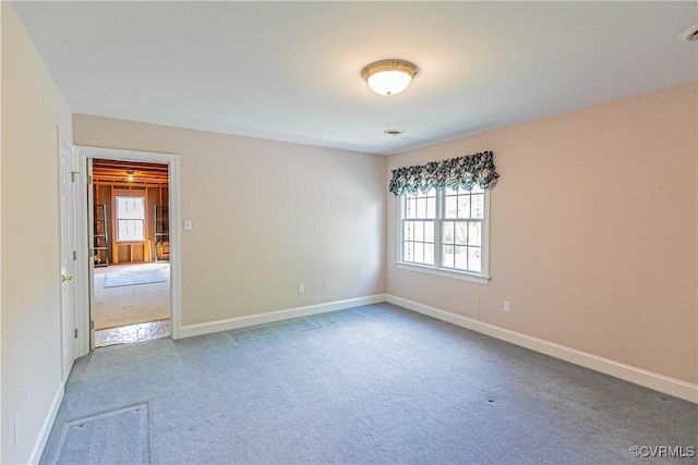 carpeted spare room featuring baseboards