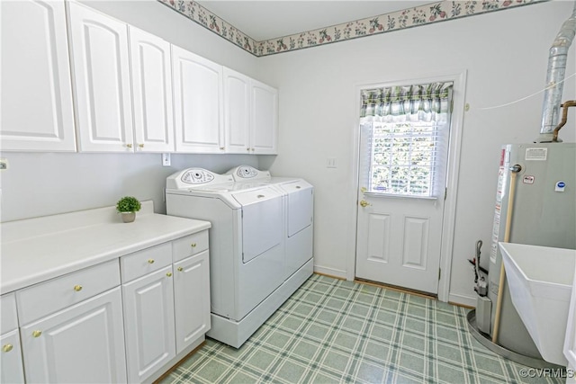 clothes washing area with light floors, cabinet space, independent washer and dryer, and water heater
