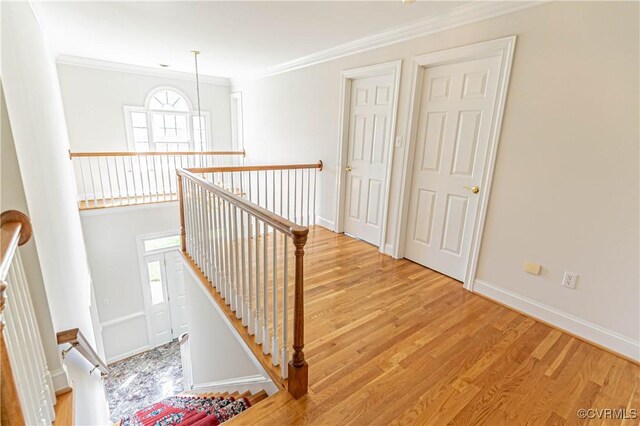 staircase featuring crown molding, baseboards, and wood finished floors