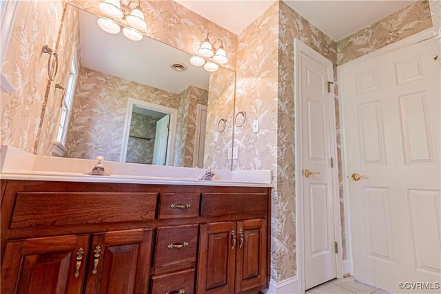 bathroom featuring vanity, wallpapered walls, and visible vents