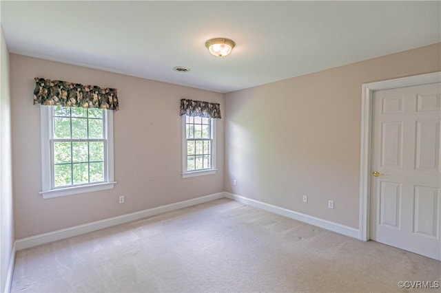 unfurnished room with baseboards, visible vents, and light colored carpet